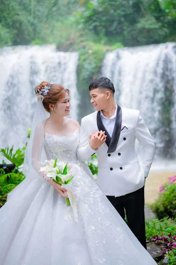 Cặp đôi nhìn nhau và nắm tay bên thác nước