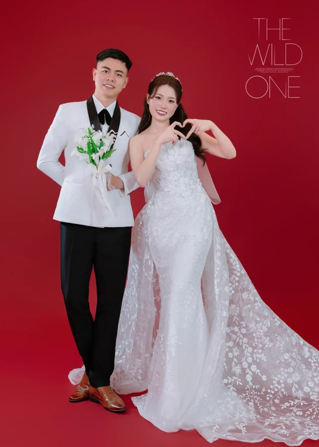Cặp đôi tạo hình trái tim trên nền đỏ, cô dâu mặc váy ren tà dài